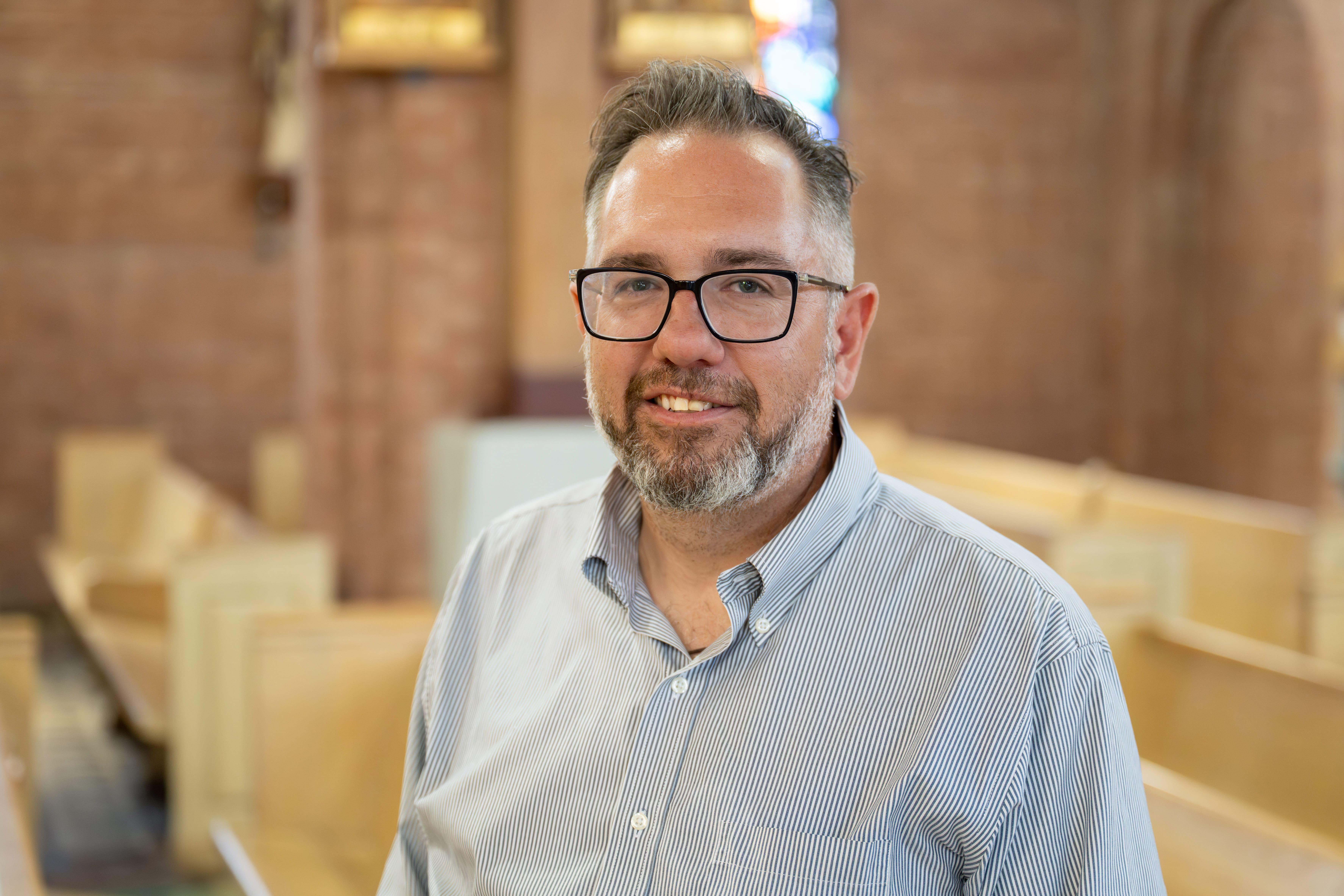 Headshot of Patrick Mason standing in Church.