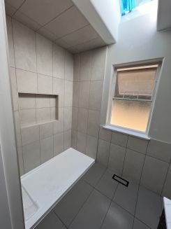 a walk in shower with an acrylic base base. Tile installed floor to ceiling