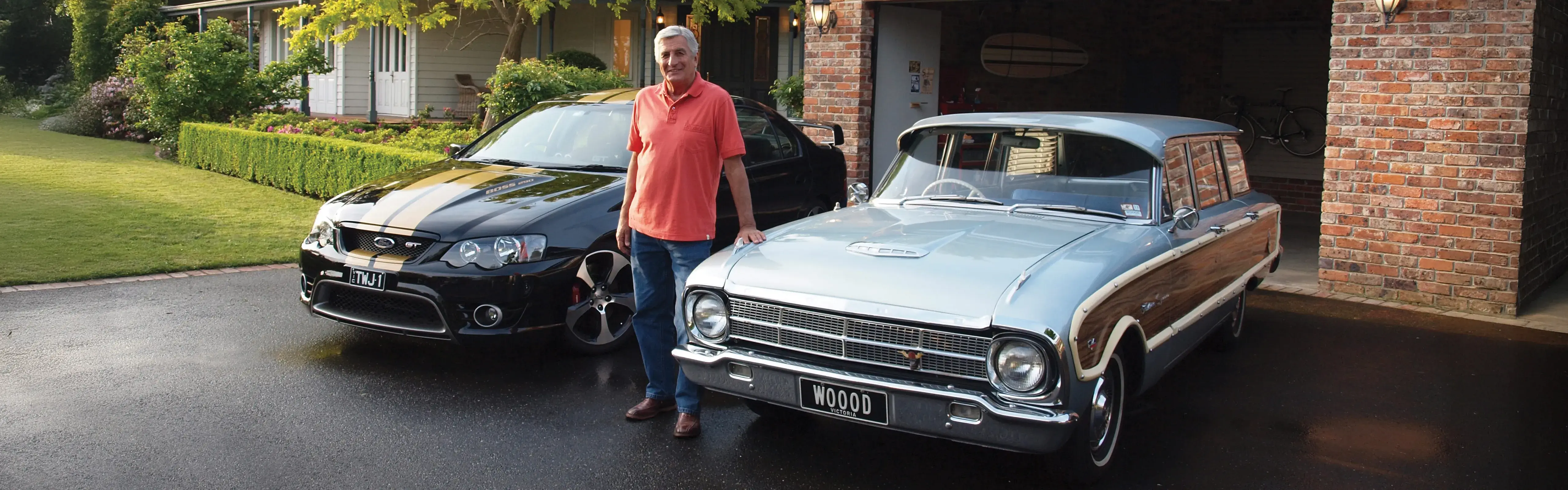 Classic car owner standing proudly in driveway with his black Ford GT and silver Ford Falcon wagon, featured in Shannons Insurance for Motoring Enthusiasts TV commercial.