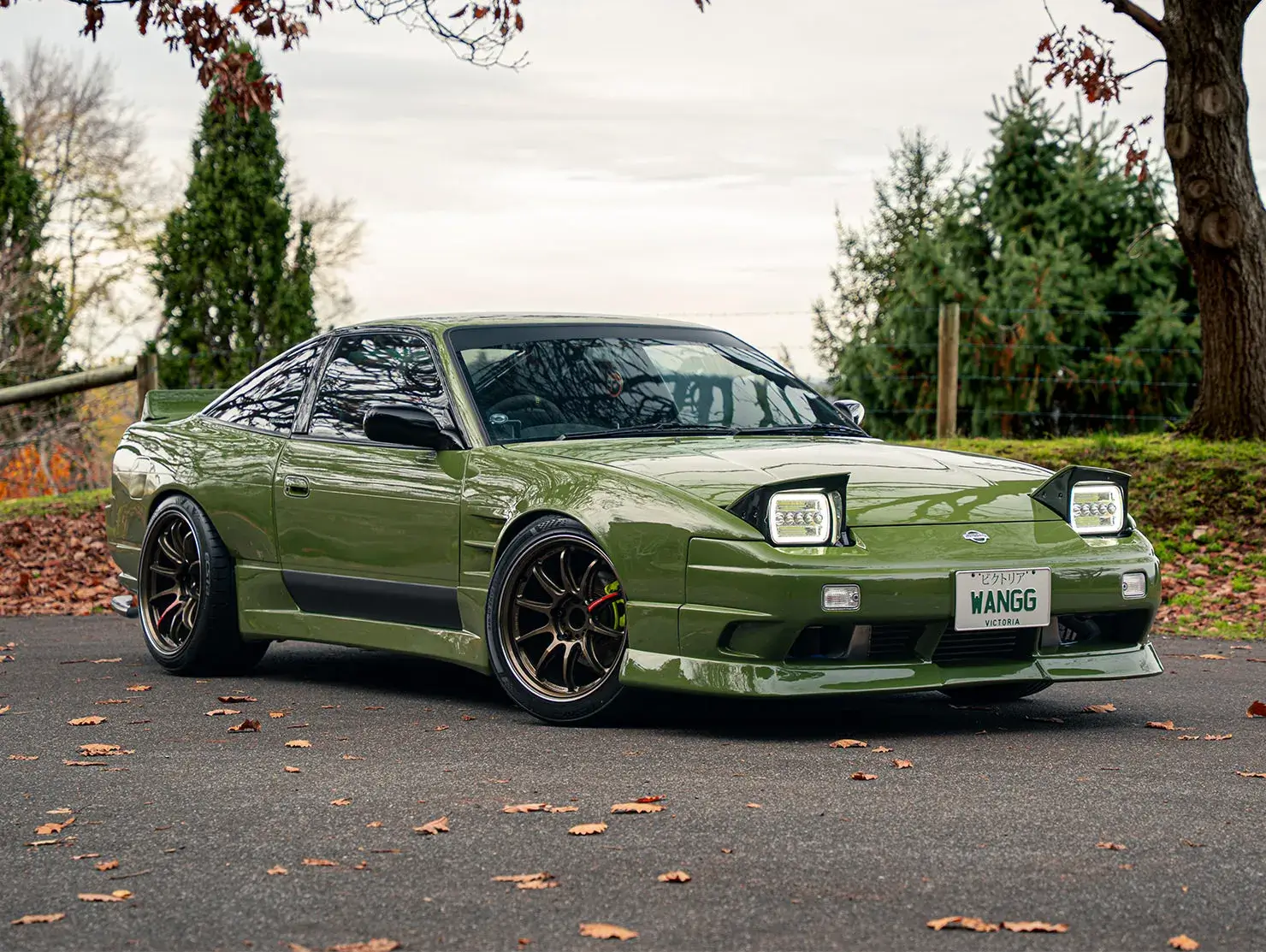 Green modified Nissan Silvia S13 with black wheels and pop-up headlights, parked outdoors - Shannons Vehicle Photography