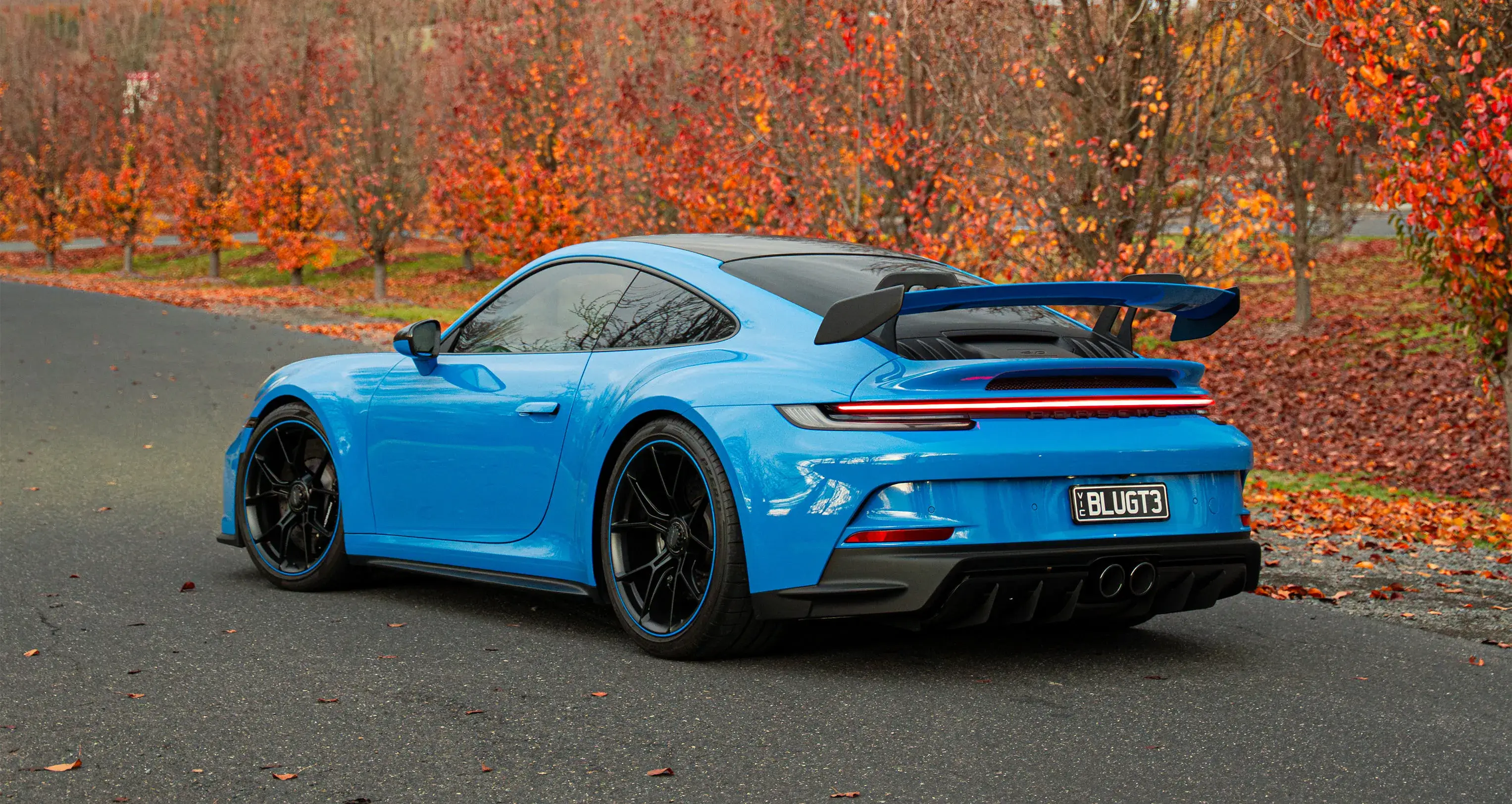 Blue Porsche 911 GT3 sports car with rear spoiler, photographed on a road with autumn leaves - Shannons Vehicle Photography