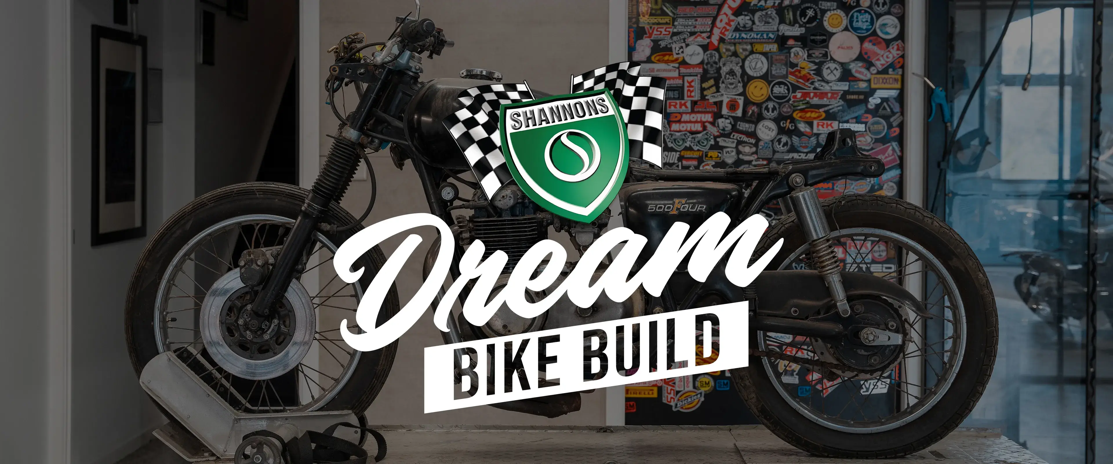 A vintage motorcycle sits on a workshop bench at the start of its restoration, overlaid with the Shannons Dream Bike Build logo, marking the launch of the Shannons Dream Bike Build YouTube Series.