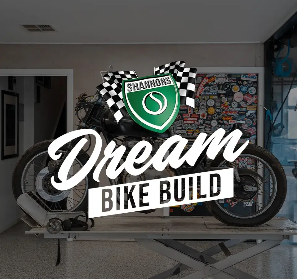 A vintage motorcycle sits on a workshop bench at the start of its restoration, overlaid with the Shannons Dream Bike Build logo, marking the launch of the Shannons Dream Bike Build YouTube Series.