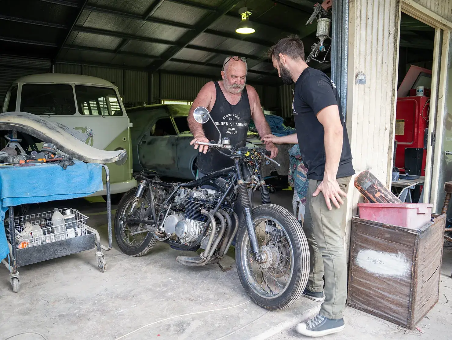 Tom from Purpose Built Moto chats with Honest Dave, while inspecting the motorcycle in his shed, captured as part of the Shannons Dream Bike Build YouTube Series.