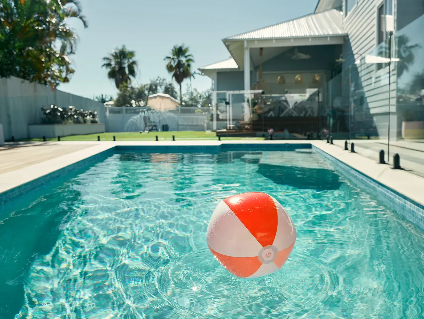 Orange and white beach ball floating in swimming pool at a holiday rental property, featured in Terri Scheer campaign.