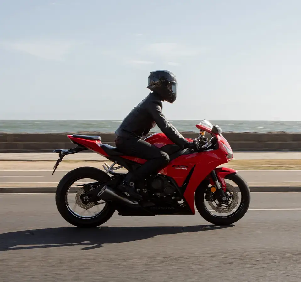 Rider on a Honda sports motorcycle cruising along a coastal road with the ocean in the background, featured as part of the Shannons Bike Insurance campaign.