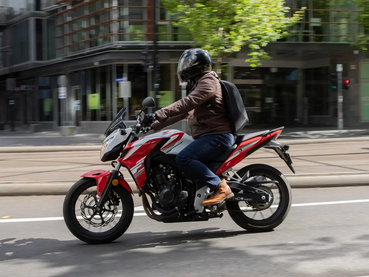 Urban commuter riding a red and white motorcycle through the city, representing everyday riders as part of the Shannons Bike Insurance campaign.