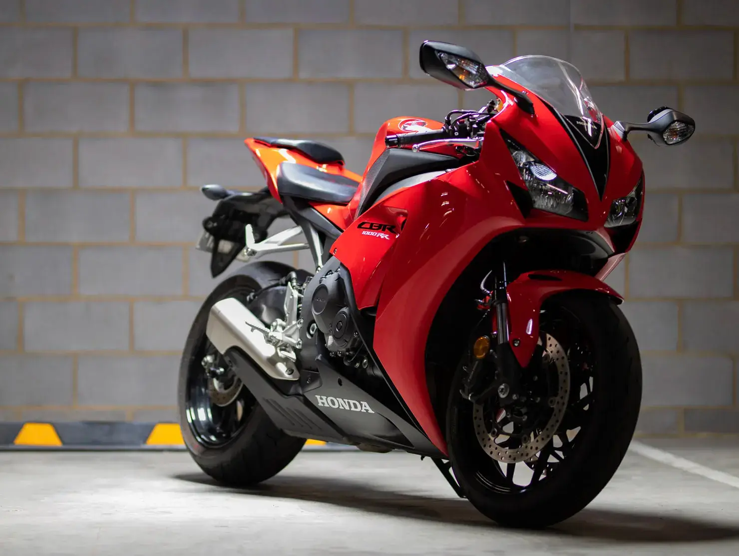 A red Honda CBR sportbike parked in an urban garage, photographed as part of the Shannons Bike Insurance campaign.