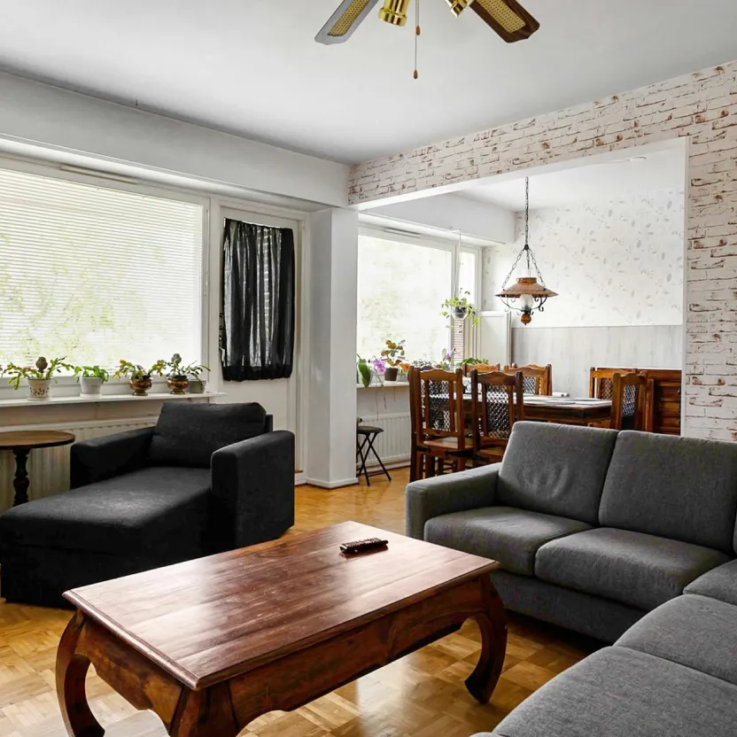 Modern living room with wood floors, a wood coffee table, and dark grey sofas