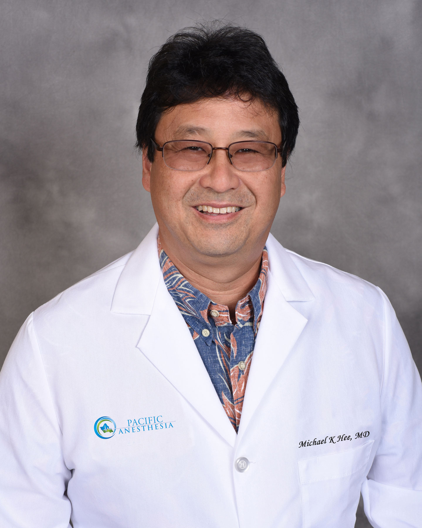 Smiling man wearing glasses and a white medical coat over a patterned shirt with Pacific Anesthesia logo and name Michael K Hee, MD.