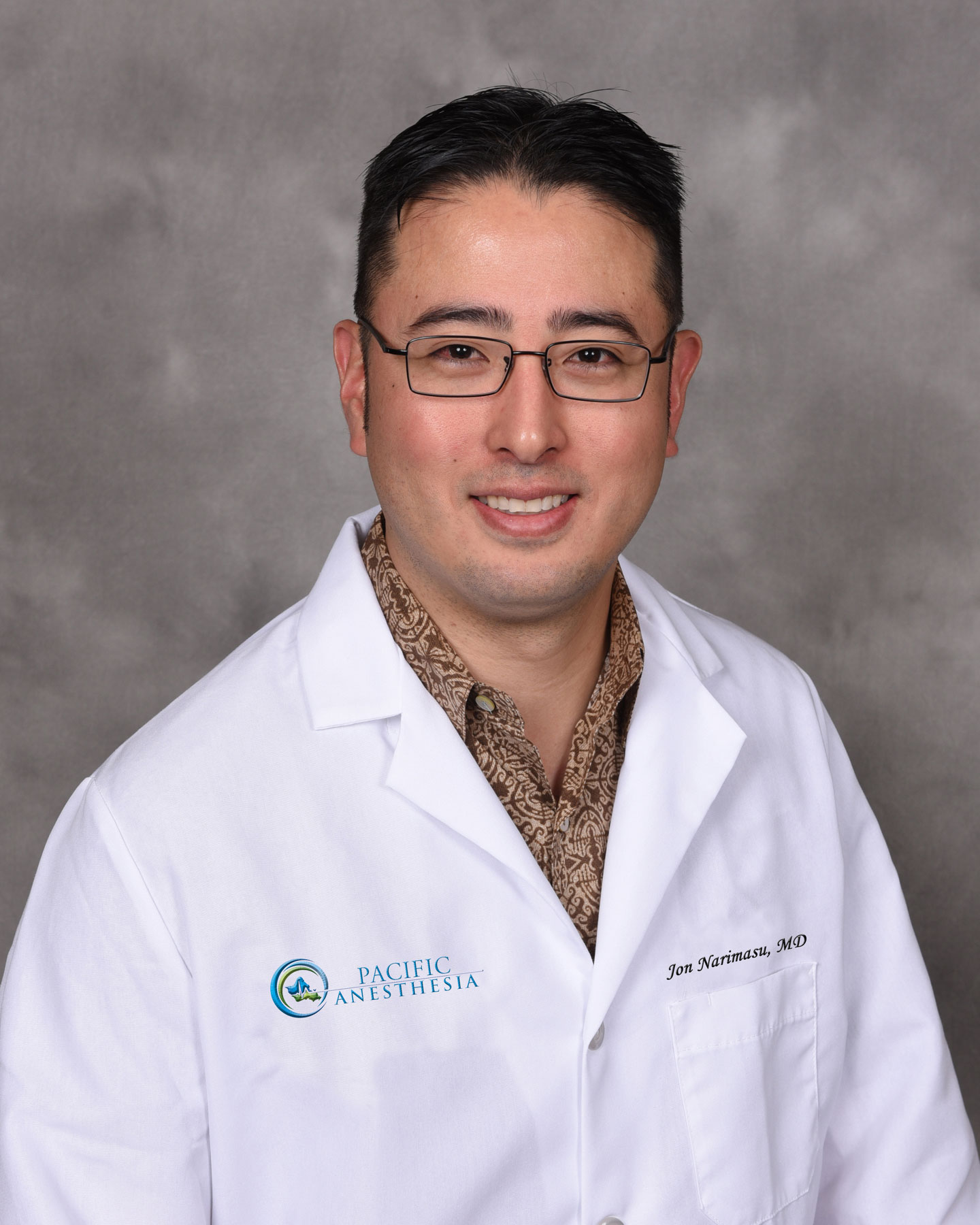 Smiling man wearing glasses and a white lab coat with the name Jon Narimasu, MD, and Pacific Anesthesia logo.