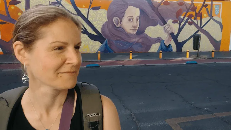 Spanish language instructor in Puebla, Mexico, smiling in front of a colorful street mural with a lookalike painted figure—one of Gringo Language Academy’s many cultural immersion experiences.