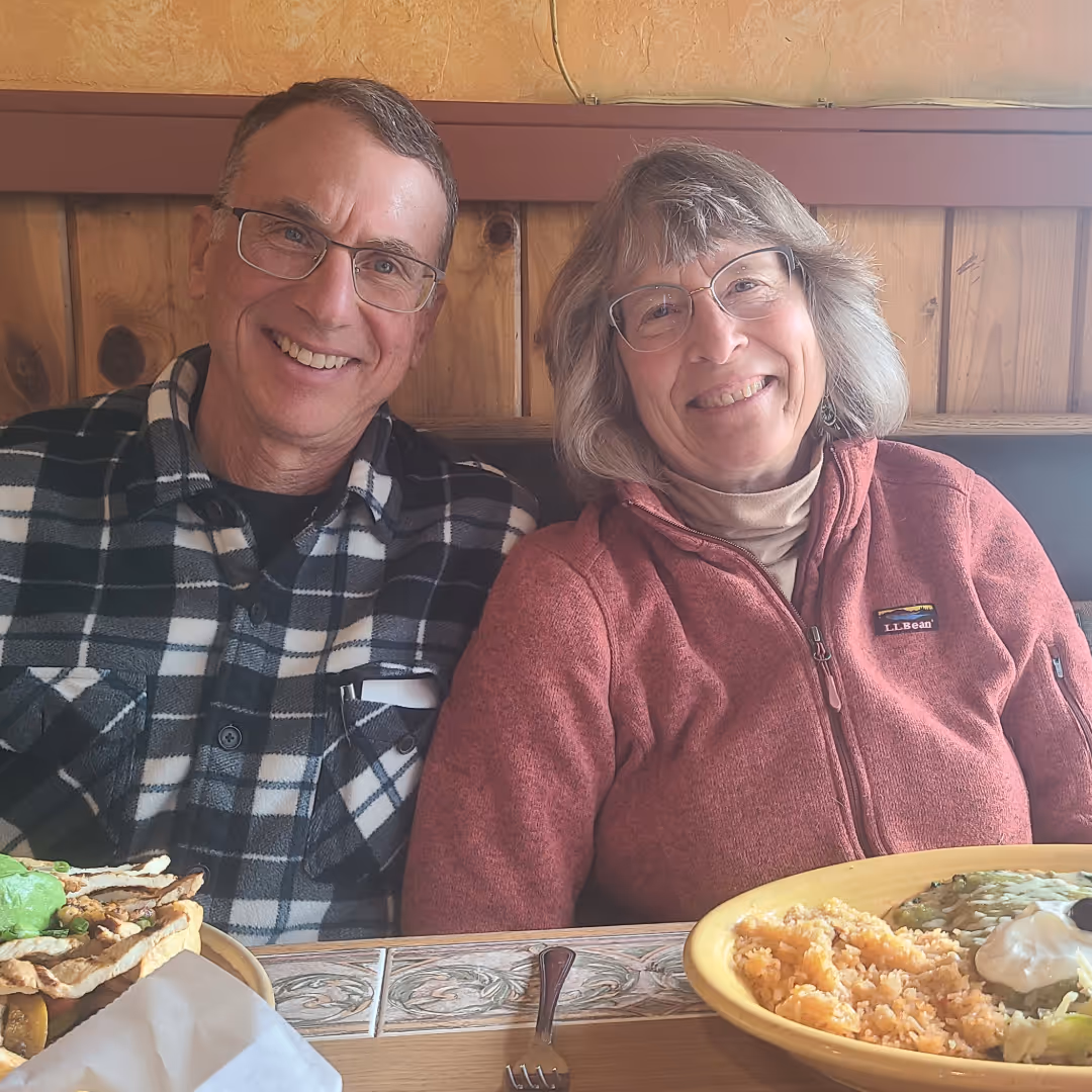 Smiling retired couple seated in front of a delicious spread of Mexican food at El Caporal—part of a Gringo Language Academy community outing in Sunriver, Oregon.