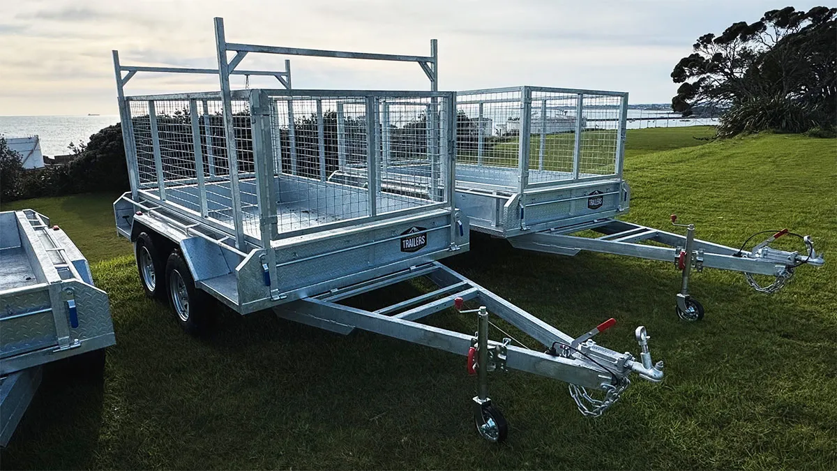 Two metal trailers with mesh sides parked on grass