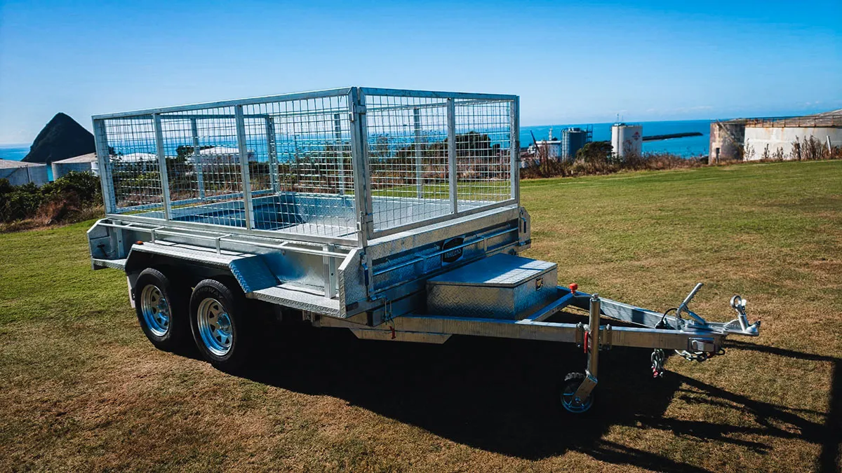 Metal utility trailer with cage sides parked on grass