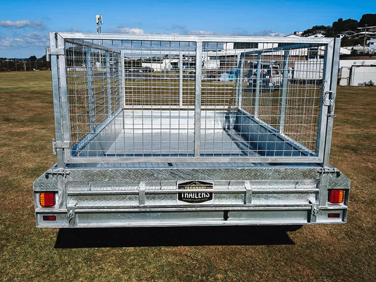 Rear view of an empty metal utility trailer with high mesh sides on a grassy field.