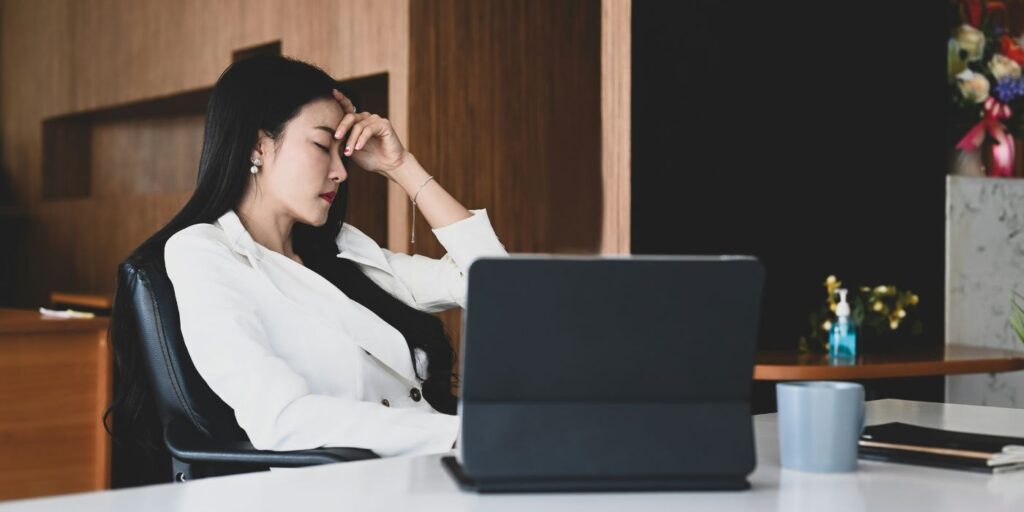 woman looks exhausted sat next to tablet