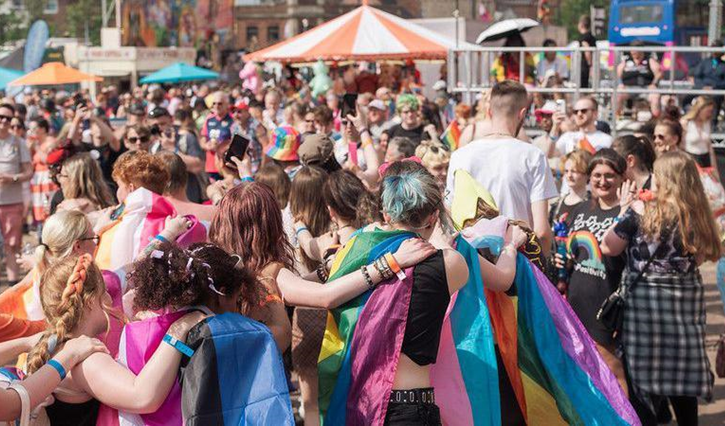 A crowd of people at a community event wearing LGBTQ flags