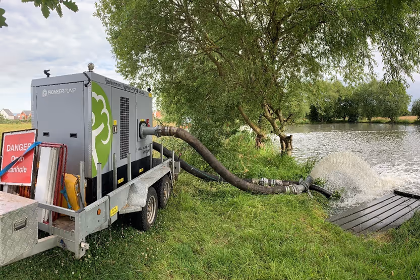 A water pump next to a lake.