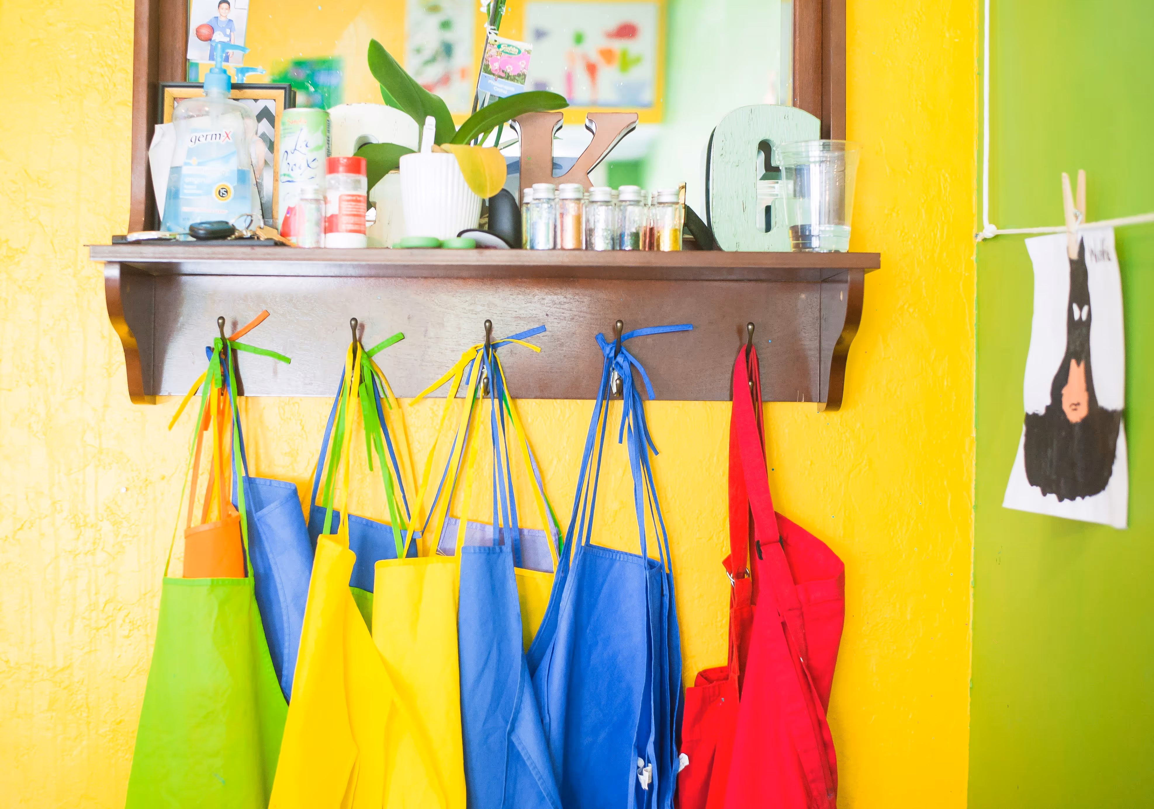 Colourful aprons hung on hooks in a school.