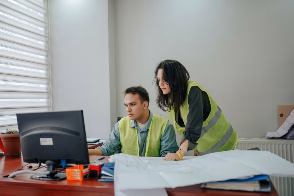 two people in high vis jackets looking at a computer