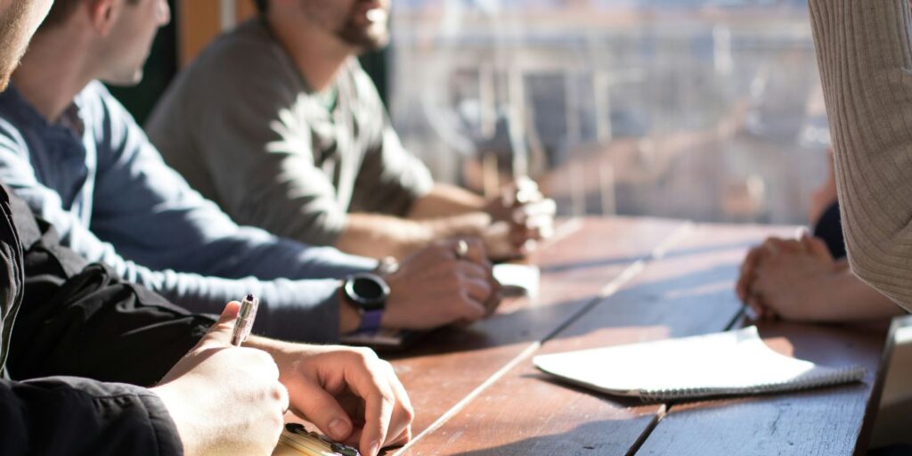 people sat around a table participating in democratic discussion