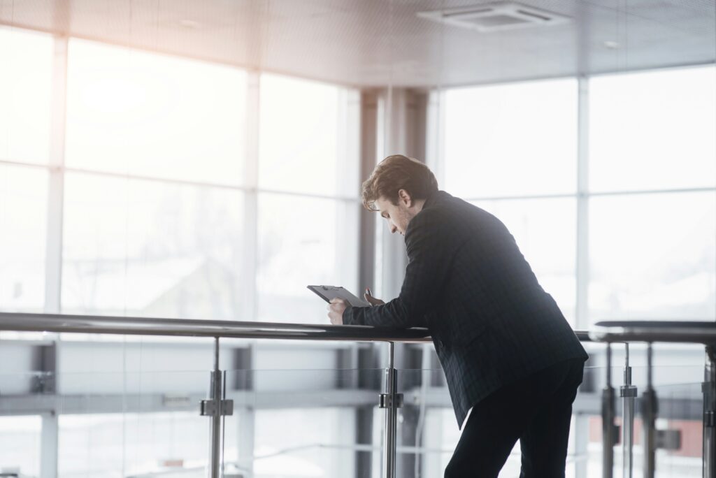 man leaning over a desk looking at a tablet
