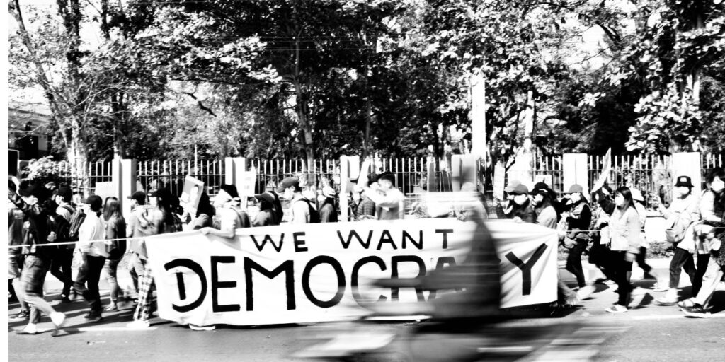 crowd holding a sign saying we want democracy