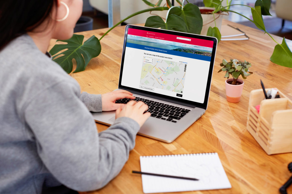 woman sat at desk looking at Delib on laptop screen participating