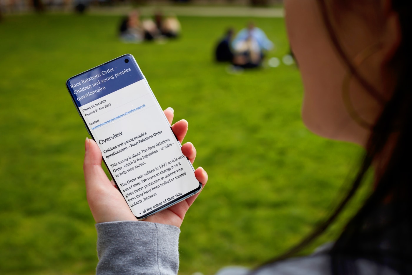 a woman looking at a mobile phone with an overview of a questionaire 