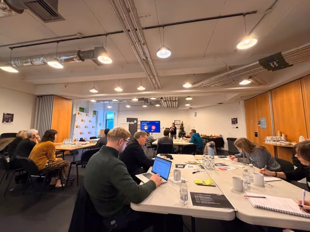 People gathered for Delib's user group, sat at large tables with pens, paper and laptops