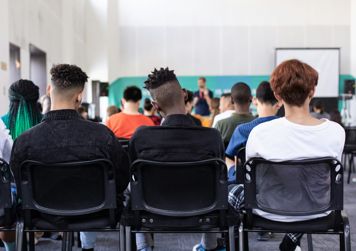 a backshot of a group of people sat in a town hall 