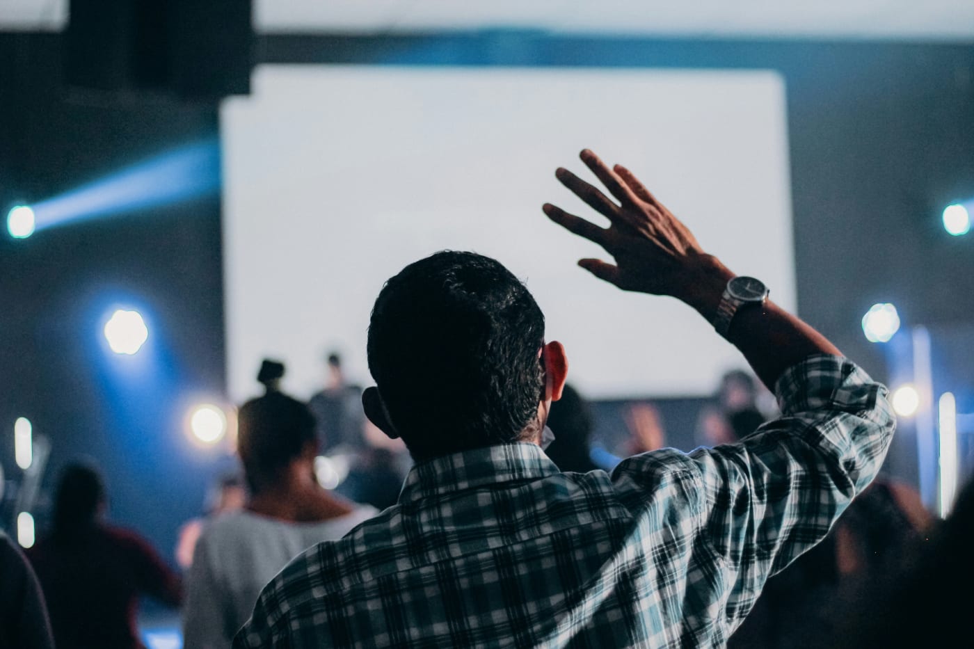 man raising his hand at a large conference