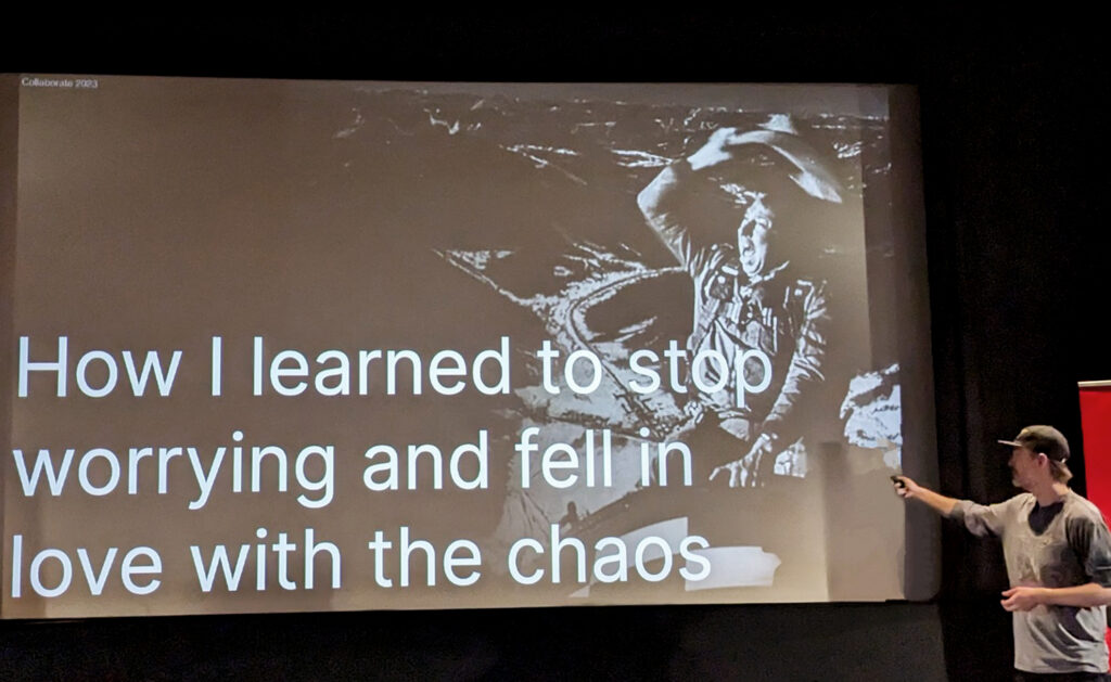 Designer Nils Bjorn presents in front of a large screen showing a slide that says 'How I learned to stop worrying and fell in love with the chaos'.