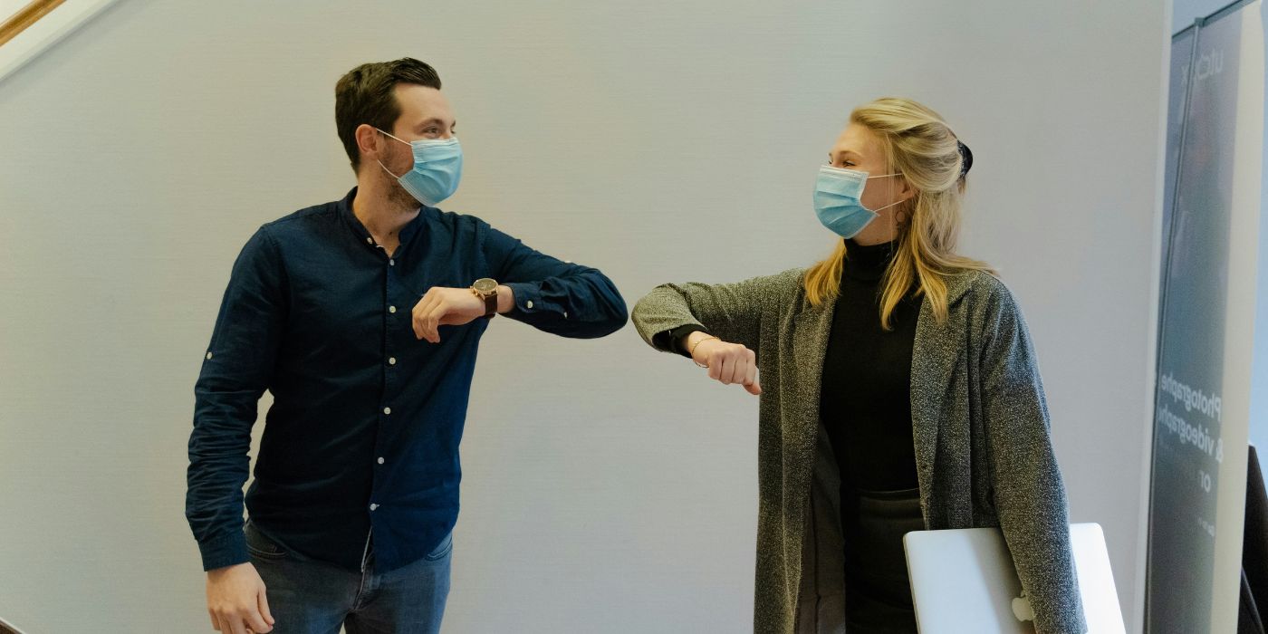 two people in masks touching elbows during covid