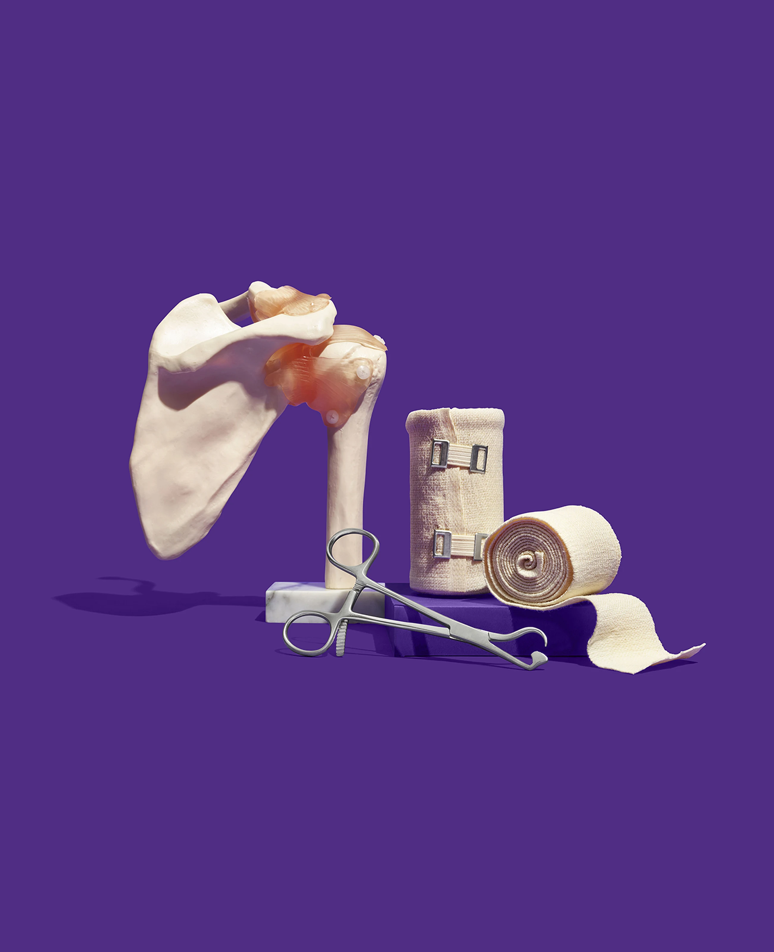 A beautifully designed photograph of a human bone, gauze and a medical apparatus set against a purple background. This is a brand element created for athenahealth by Colossus Creative Co.