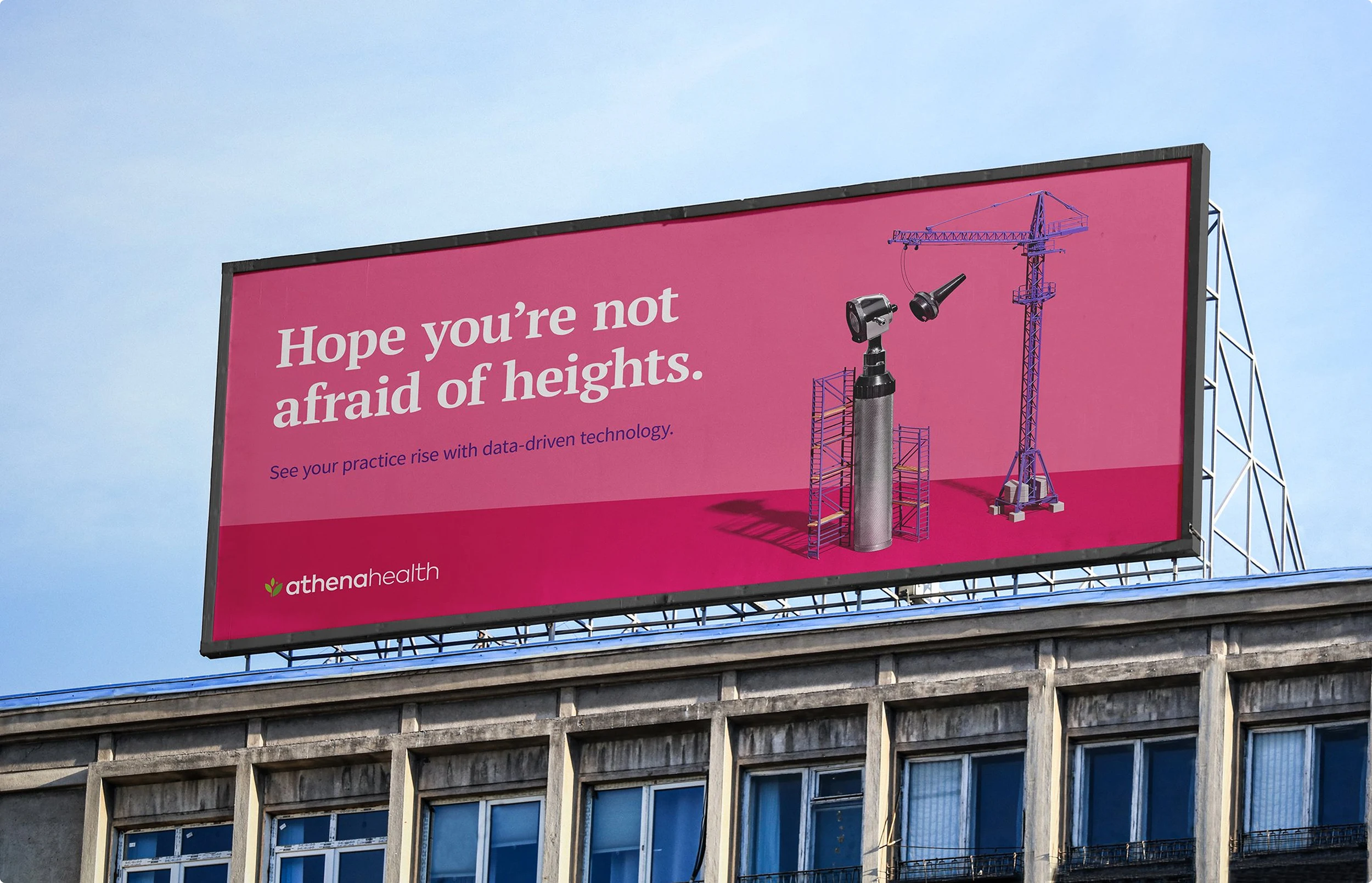 An out-of-home billboard execution for athenahealth. There is a medical device being assembled by a crane and surrounded by construction scaffolding. The headline reads "Hope you're not afraid of heights."