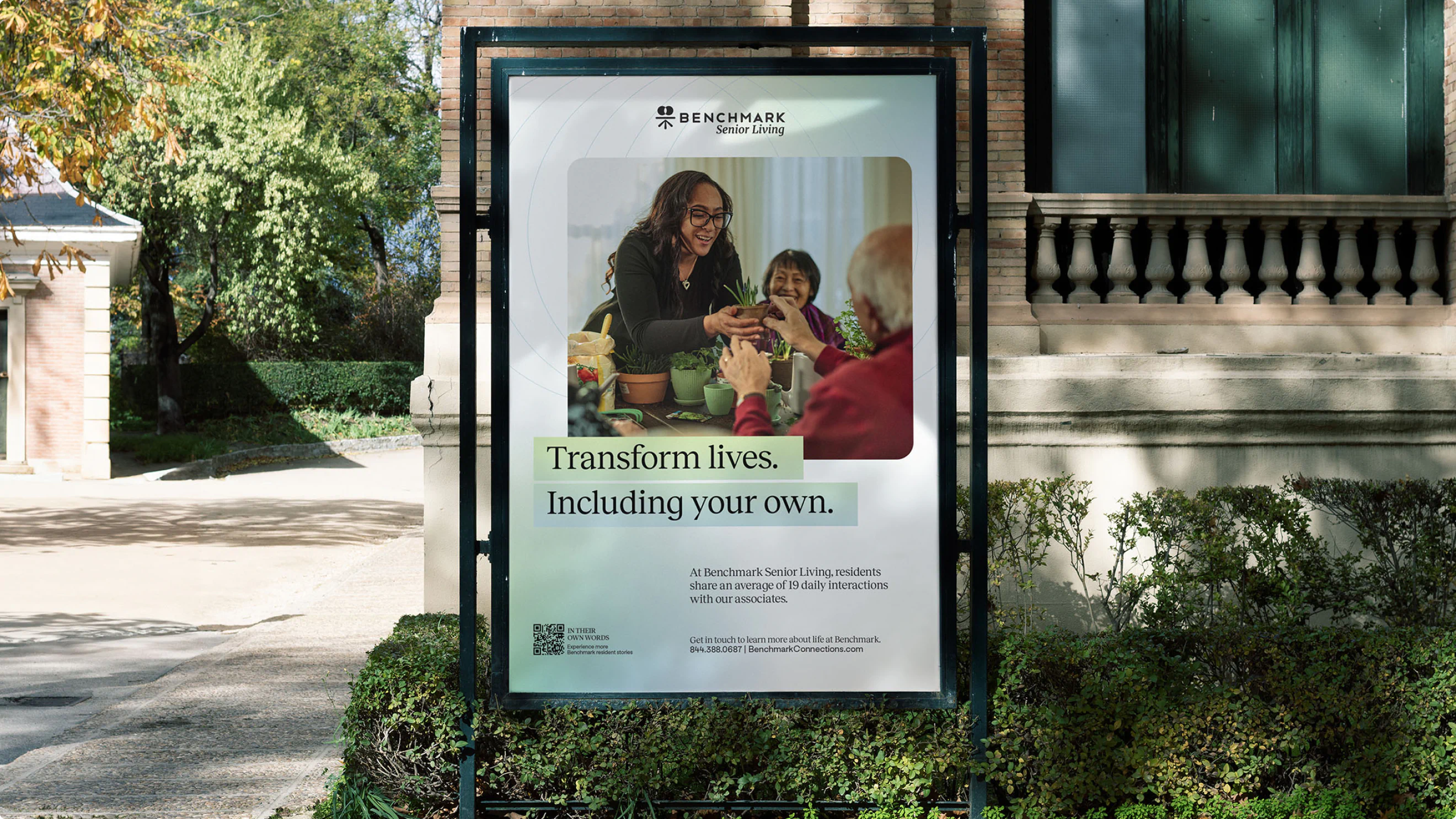 A small billboard for Benchmark Senior living in a garden setting.