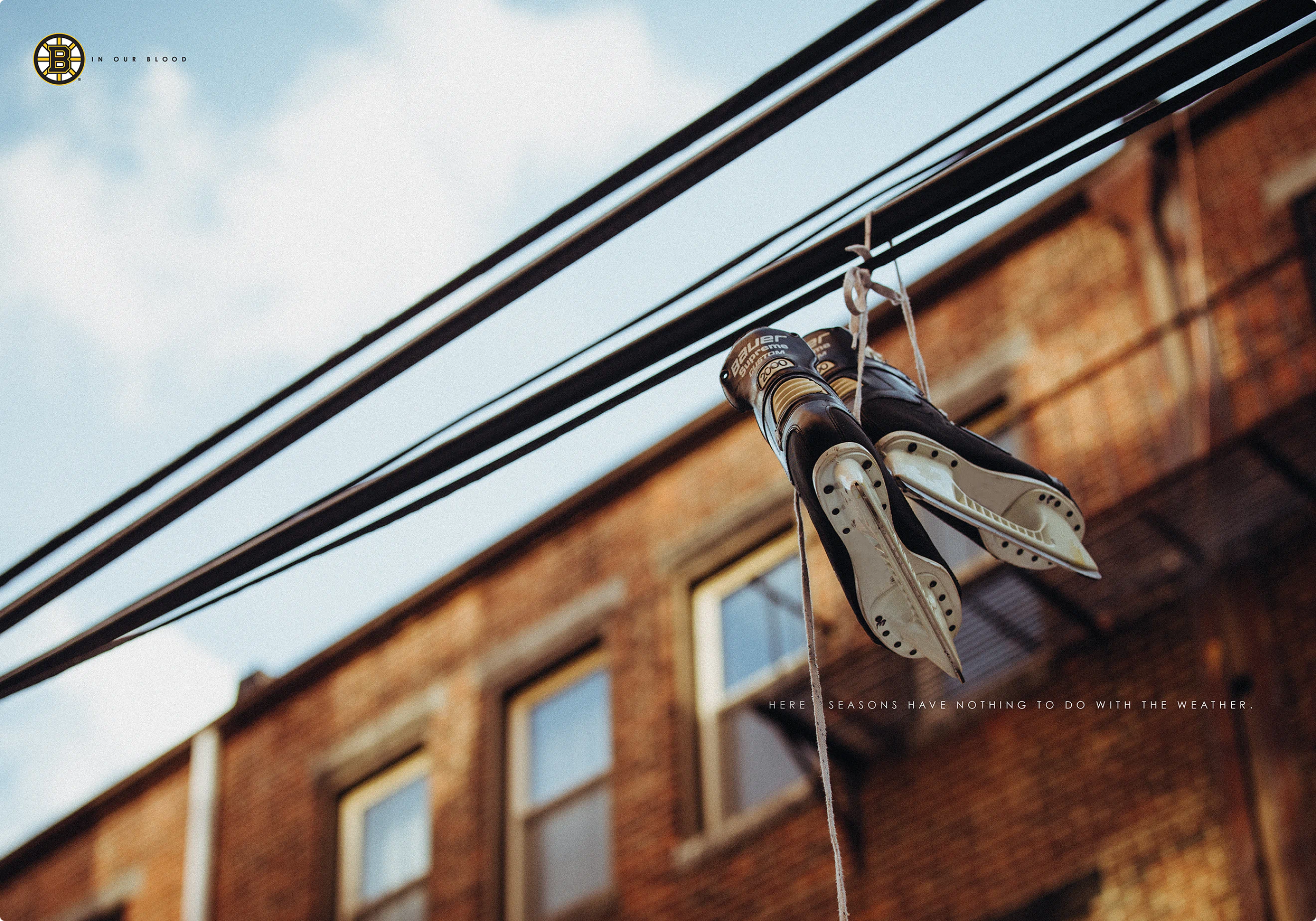 "In Our Blood" ad campaign print ad by Colossus. A picture of an old pair of hockey skates hanging over a power line.