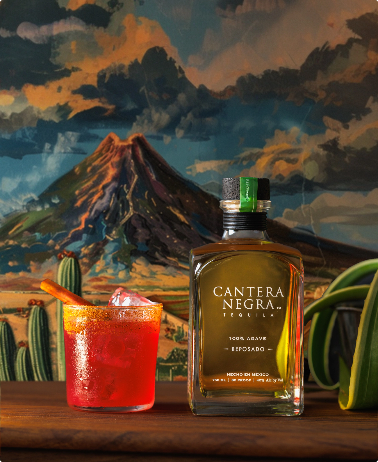 A bottle of Cantera Negra Tequila in front of a classic oil painting of a Mexican volcano.