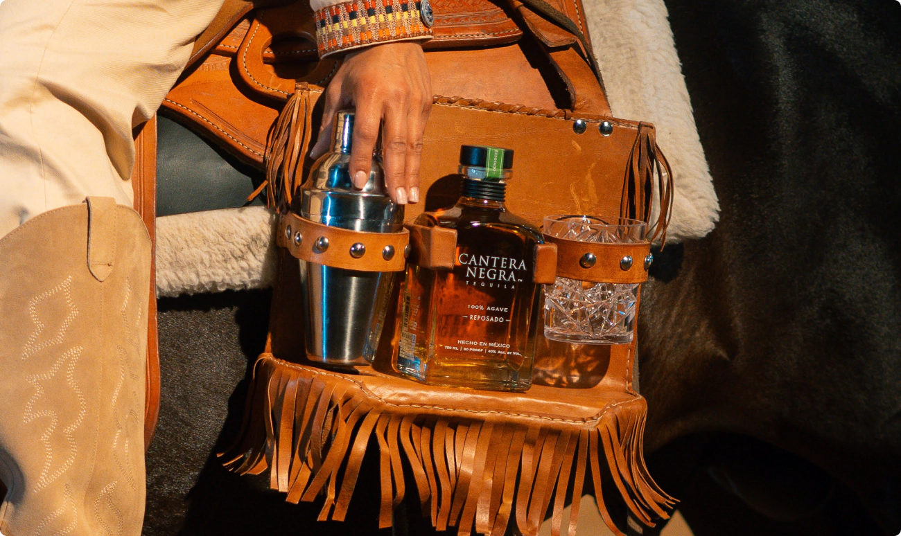 A custom made leather holster made to hold a bottle of tequila, a cocktail shaker and a rocks glass while on horseback.