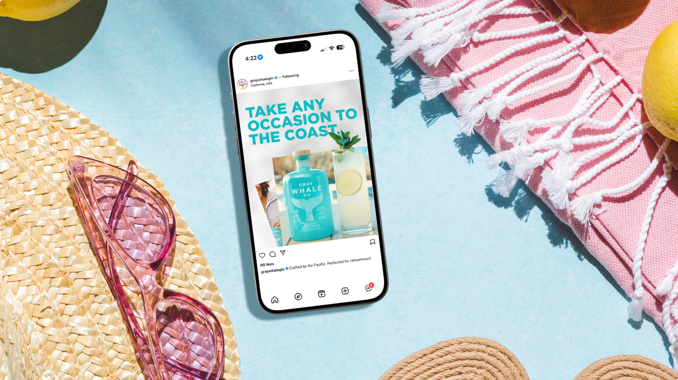 A cell phone on a beach blanket with a social post for Gray Whale Gin.