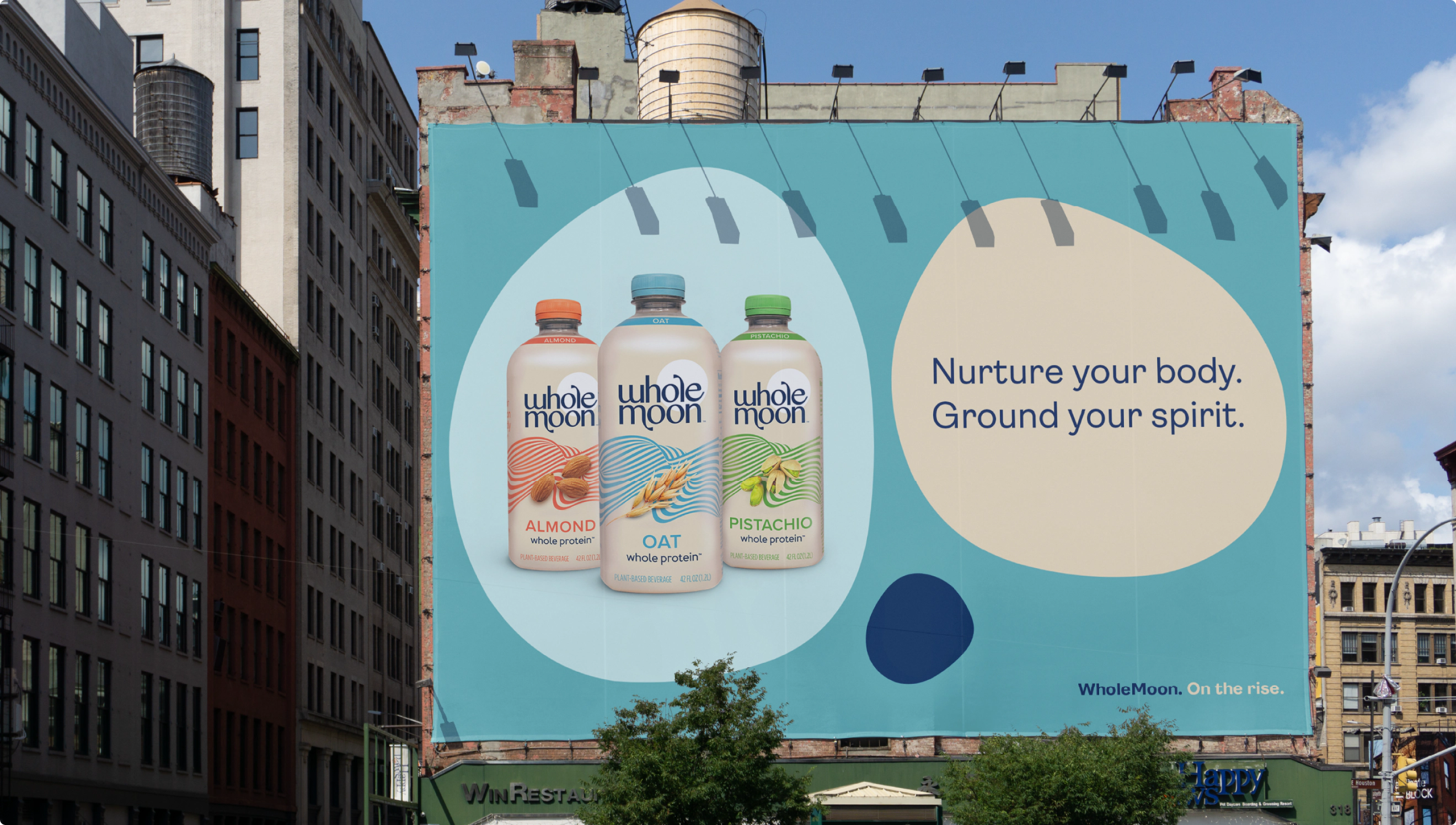 City wallscape advertisement for Whole Moon Soy Milk. The headline reads "Nurture your body. Ground your spirit."