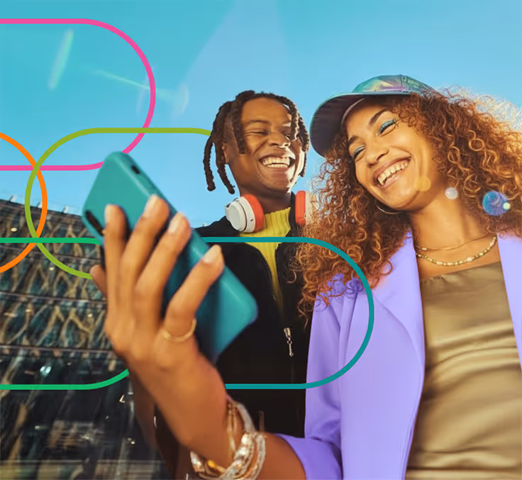 Two young adults smiling and taking a selfie outdoors on a sunny day, with colorful graphic overlays.