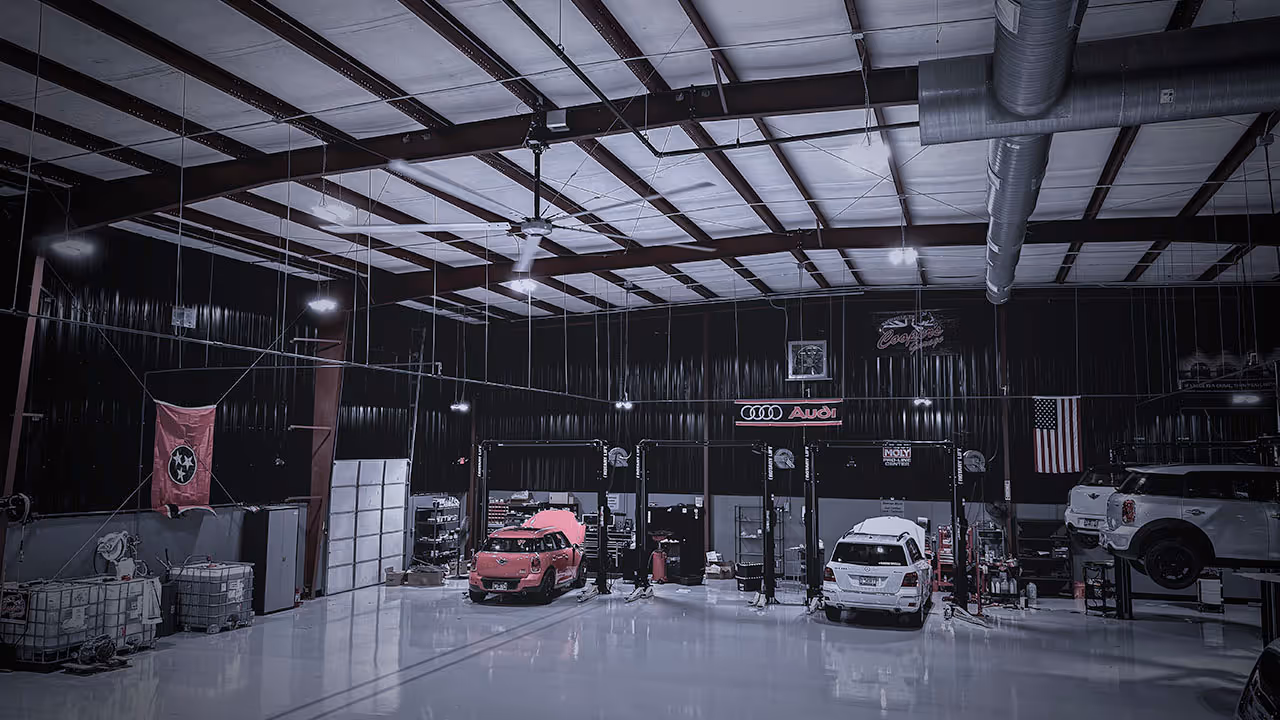 Interior view of Cooper’s Garage service bay with vehicles on lifts and shop equipment visible
