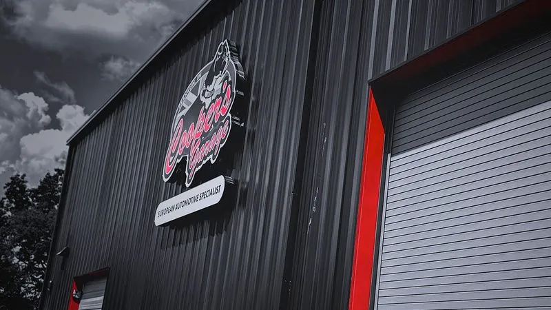 Cooper’s Garage building exterior featuring the shop logo sign and red-trimmed service bay door

