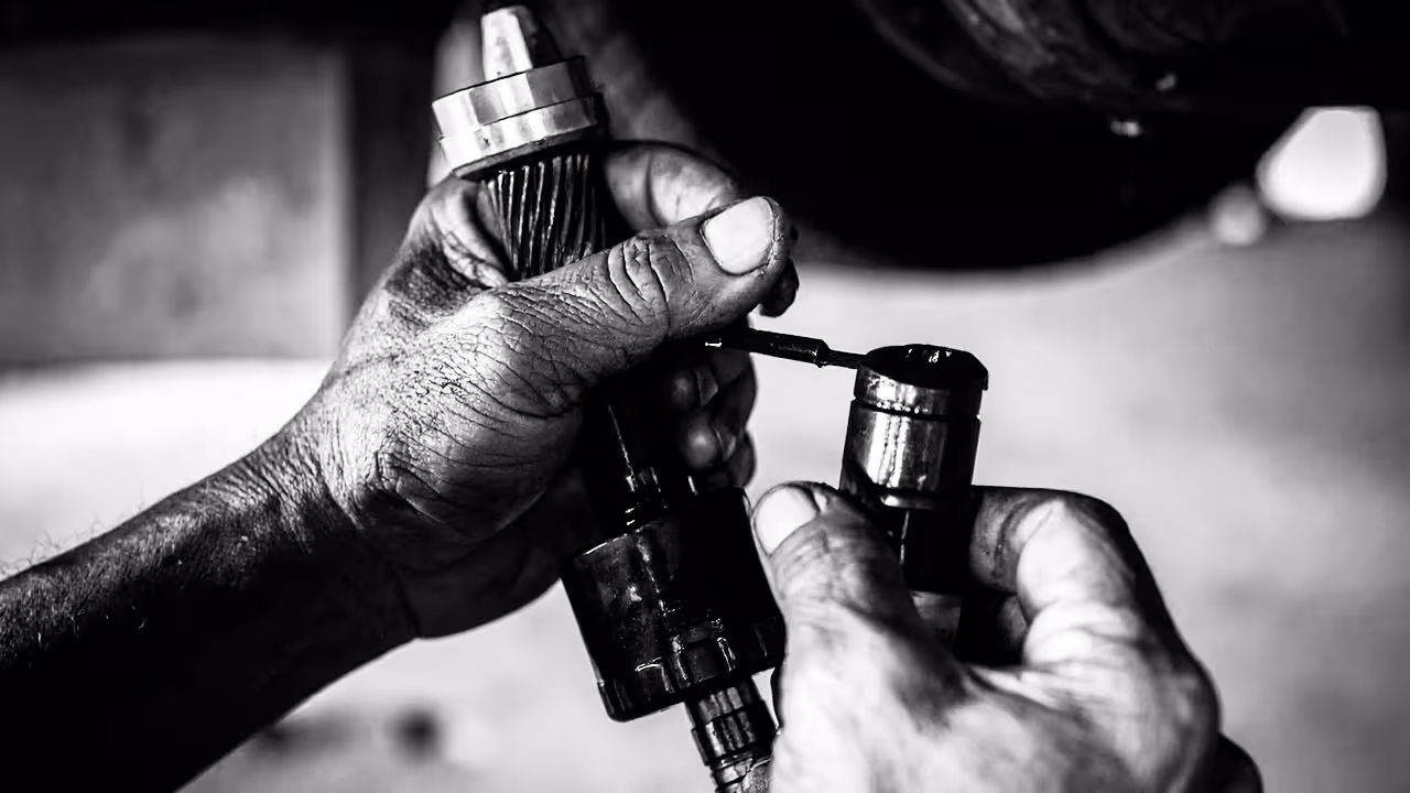 Technician performing transmission fluid exchange with fresh ATF draining from service tool — Cooper’s Garage transmission fluid exchange service to restore smooth shifting and extend gearbox life in European vehicles.