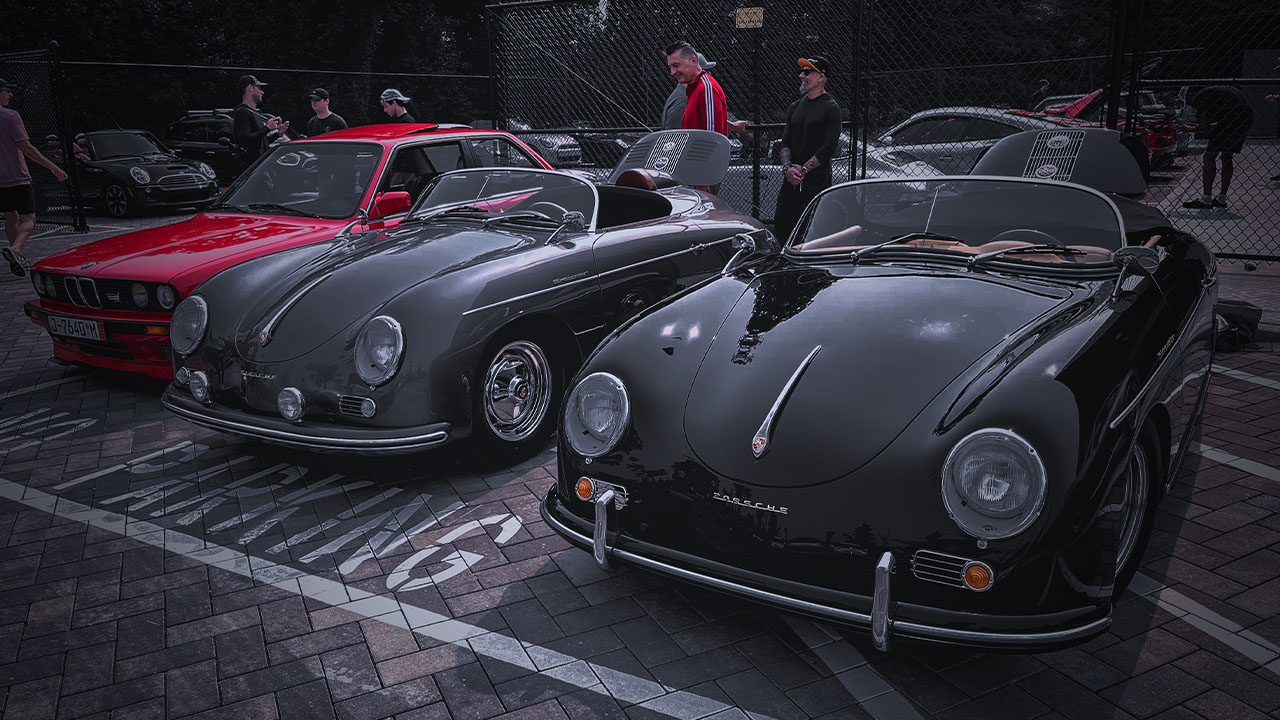 Vintage Porsche Speedsters and a classic red BMW E30 on display at a Cooper’s Garage Cars & Coffee event, with attendees gathered nearby.