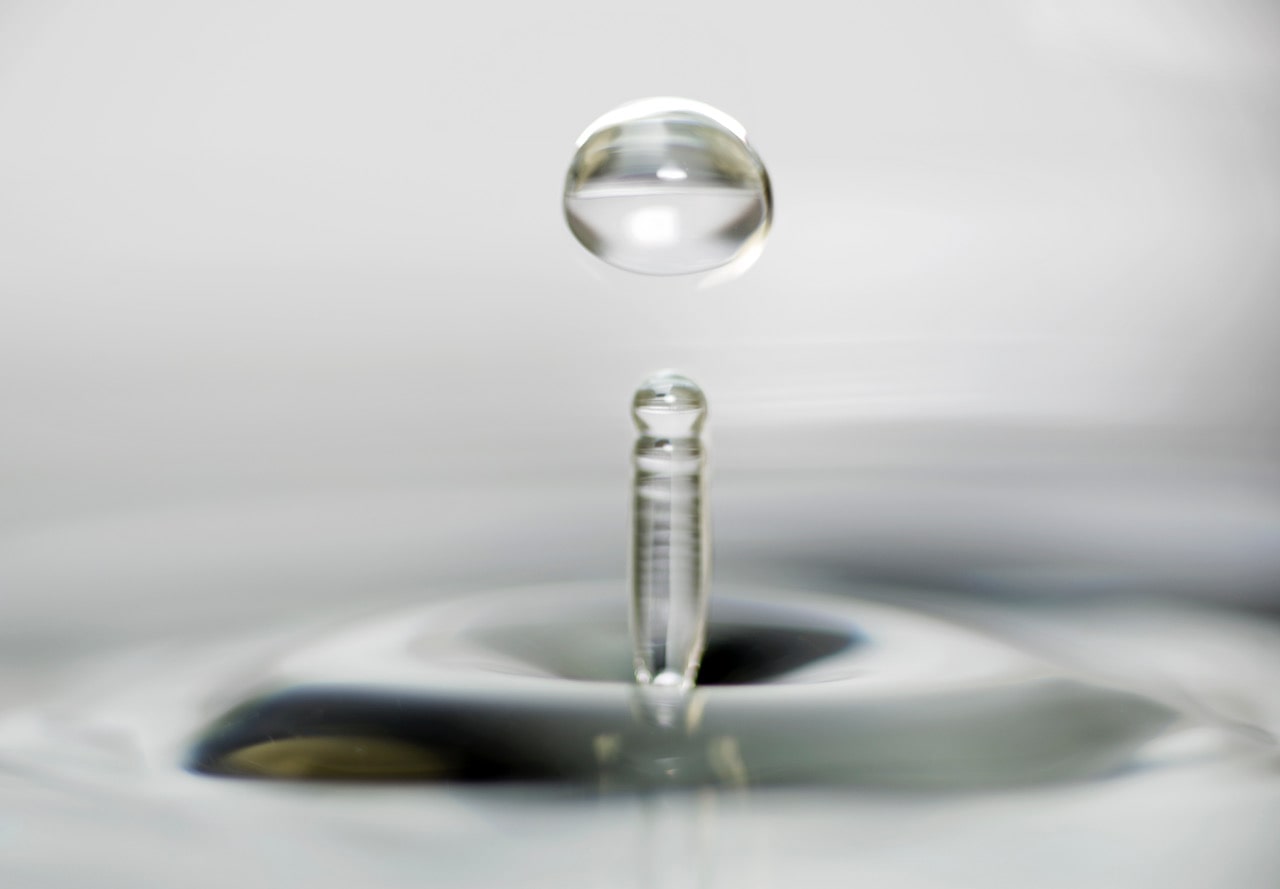 Nahaufnahme eines fallenden Wassertropfens über einer Wasseroberfläche, Teil des Webdesign-Projekts Vèora Beauty in München