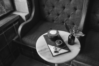 Schwarz-Weiß-Foto einer gemütlichen Café-Ecke mit Cappuccino und Gebäck, Teil des Webdesign-Projekts Nordseekollektiv in Köln